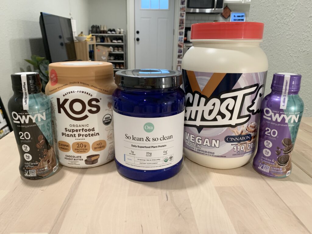 kos plant protein, ora plant protein, ghost plant protein, and owyn plant protein side by side on table