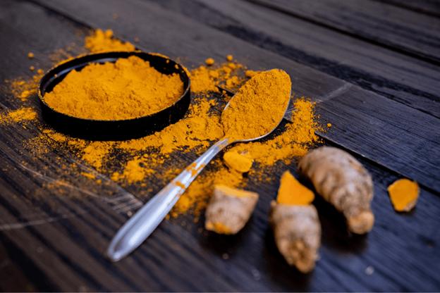 Turmeric powder on spoon and whole turmeric root